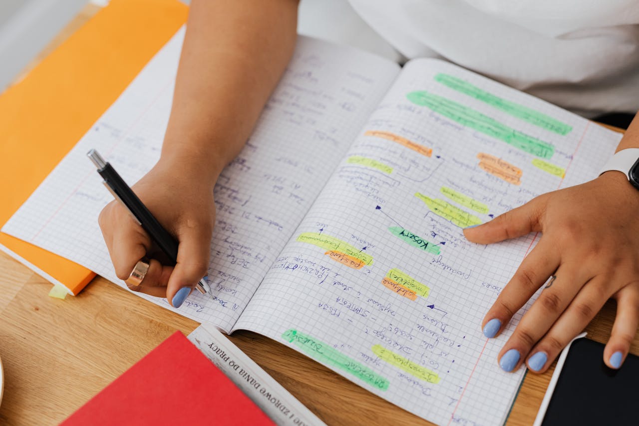 brand-01 A person writing and highlighting notes in a graph notebook. Ideal for education and productivity themes.