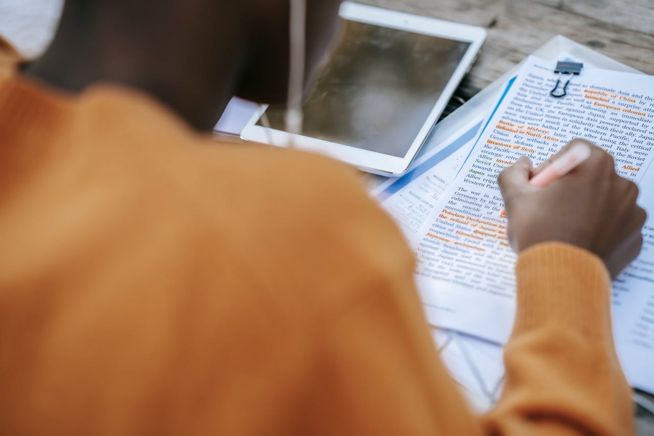 brand-02 From above of crop anonymous African American person outlining text at table with tablet with black screen