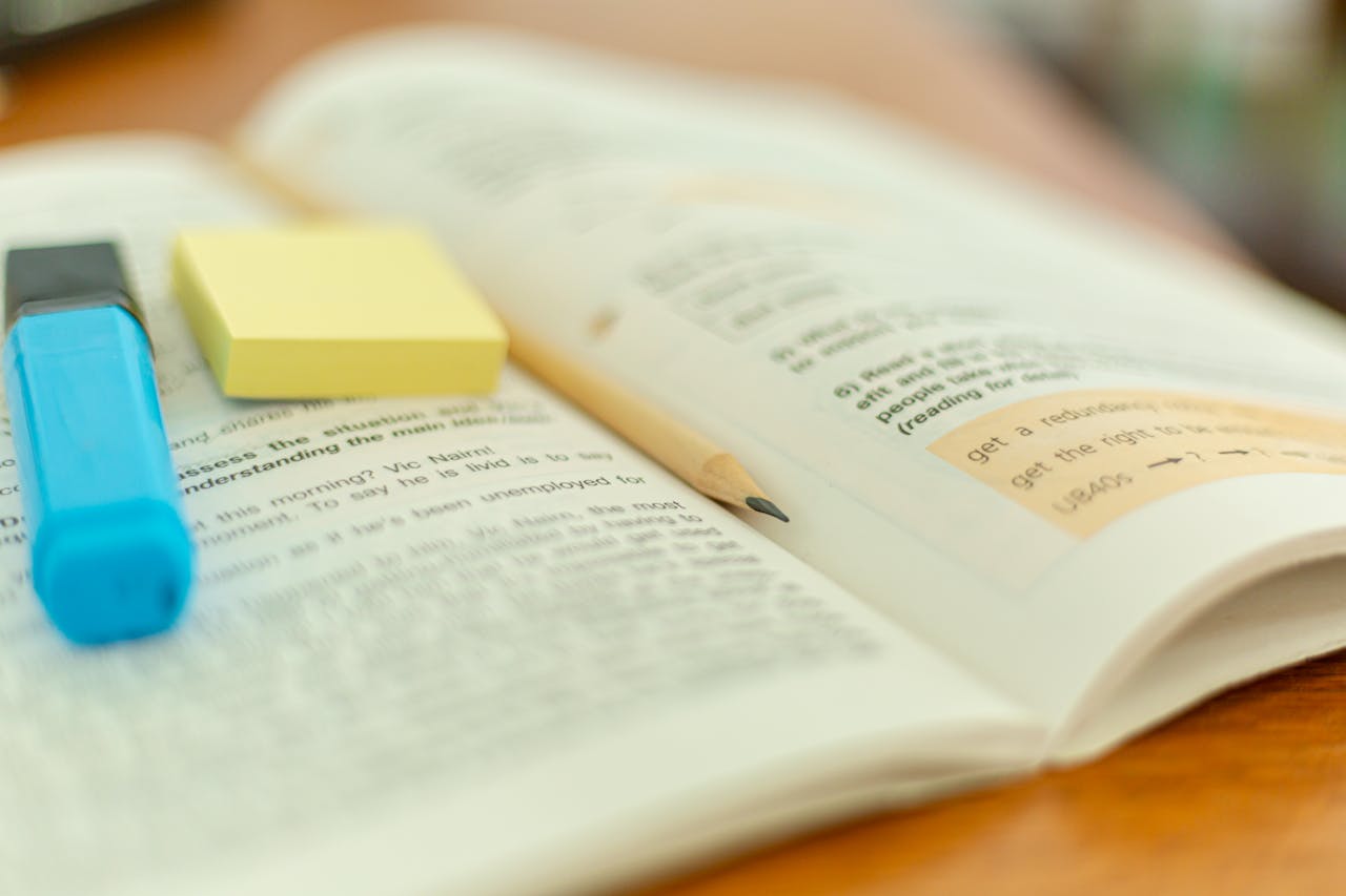 brand-03 Close-up of an open book with a highlighter and sticky notes for study reference.